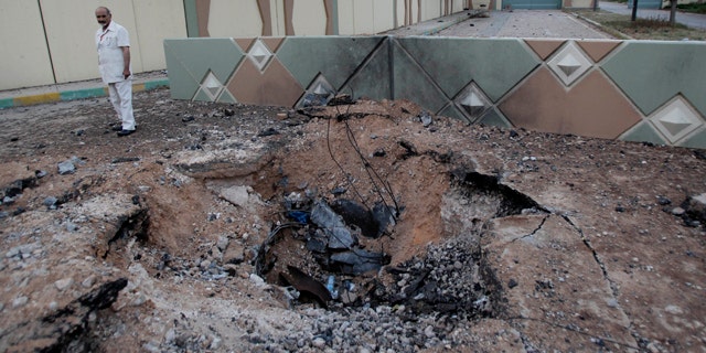 June 1: In this photo taken on a government organized tour, a Libyan official stands next to a crater left after an airstrike at Muammar al-Qaddafi's Bab al-Aziziya compound, a regular target of NATO airstrikes, in Tripoli, Libya.