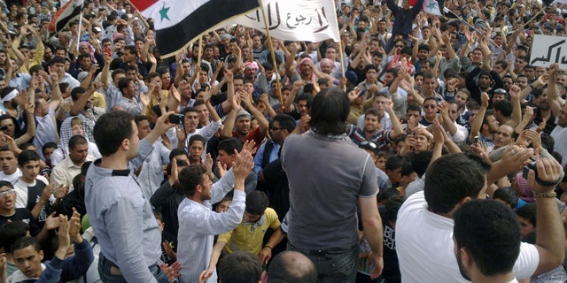 May 29: In this citizen journalism image made on a mobile phone and provided by Shaam News Network, Syrian anti-regime protesters carry national flags and banners during a rally in Talbiseh, in the central province of Homs, Syria.