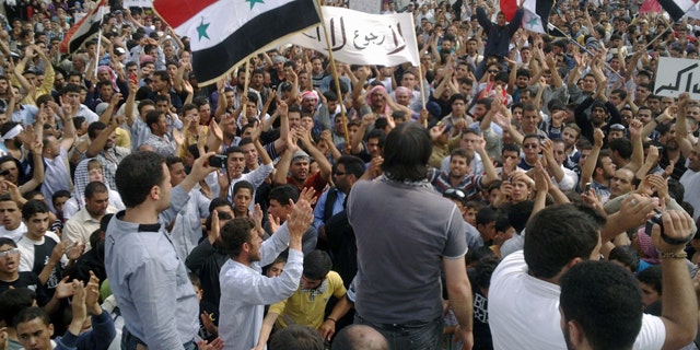 May 29: In this citizen journalism image made on a mobile phone and provided by Shaam News Network, Syrian anti-regime protesters carry national flags and banners during a rally in Talbiseh, in the central province of Homs, Syria.