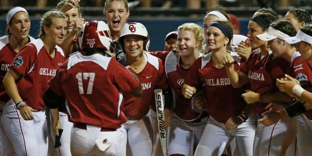 Oklahoma infielder Shay Knighten (17) is greeted at the plate by her teammates after hitting a home run in the seventh inning of an NCAA Women's College World Series softball game against LSU in Oklahoma City, Sunday, June 5, 2016. Oklahoma won 7-3. (AP Photo/Sue Ogrocki)