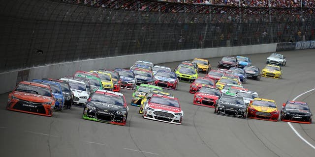 BROOKLYN, MI - JUNE 14: Carl Edwards, driver of the #19 ARRIS Toyota, Kasey Kahne, driver of the #5 Great Clips Chevrolet, and Ryan Blaney, driver of the #21 Motorcraft/Quick Lane Tire & Auto Center Ford, lead the field into turn one after a restart during the NASCAR Sprint Cup Series Quicken Loans 400 at Michigan International Speedway on June 14, 2015 in Brooklyn, Michigan. (Photo by Brian Lawdermilk/Getty Images)