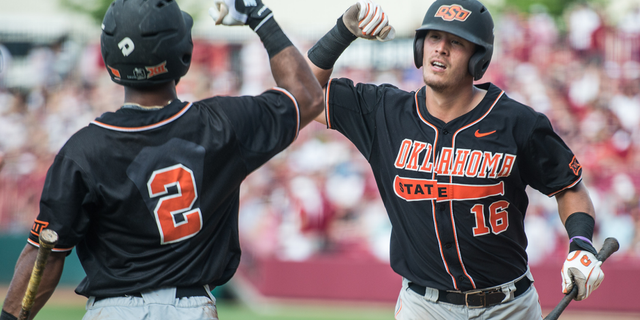 Oklahoma State catcher Collin Theroux (16) celebrates his ninth inning home run with teammate J.R. Davis (2) during an NCAA college baseball tournament super regional game against South Carolina, Saturday, June 11, 2016, in Columbia, S.C. Oklahoma State defeated South Carolina 5-1. (AP Photo/Sean Rayford)