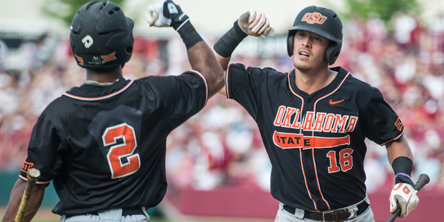Oklahoma State catcher Collin Theroux (16) celebrates his ninth inning home run with teammate J.R. Davis (2) during an NCAA college baseball tournament super regional game against South Carolina, Saturday, June 11, 2016, in Columbia, S.C. Oklahoma State defeated South Carolina 5-1. (AP Photo/Sean Rayford)