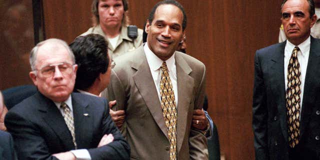 FILE - In this Oct. 3, 1995 file photo, O.J. Simpson, center, clenches his fists in victory after the jury said he was not guilty in the murders of his ex-wife Nicole Brown Simpson and her friend Ronald Goldman in a Los Angeles courtroom as attorneys F. Lee Bailey, left, and Robert Shapiro, right, look on.