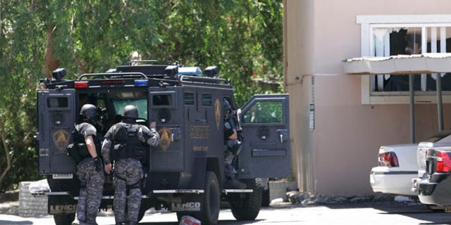 June 10: Law enforcement officers huddle behind an armored vehicle outside an apartment during day two of a hostage standoff as an armed robbery suspect barricaded himself and a 15-month-old boy in Sacramento, Calif.