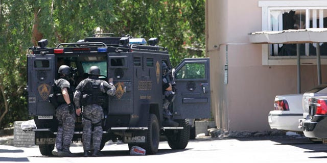 June 10: Law enforcement officers huddle behind an armored vehicle outside an apartment during day two of a hostage standoff as an armed robbery suspect barricaded himself and a 15-month-old boy in Sacramento, Calif.