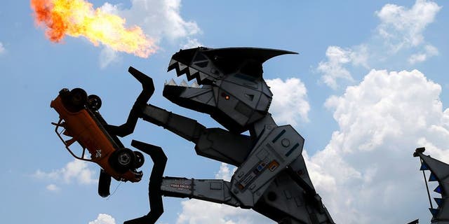 Robosaurus, a mechanical customized tractor trailer, is operated by IndyCar driver Juan Pablo Montoya and Shawn Pacheco, both located in the cockpit of the 40-foot-tall creation as it spews flames while destroying a small vehicle, Thursday, June 9, 2016, in Dallas. Montoya is scheduled to race in Saturday's Firestone 600 auto race at Texas Motor Speedway. (AP Photo/Tony Gutierrez)
