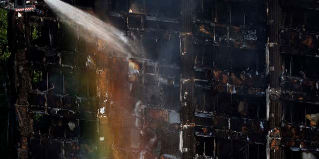 The sun creates a rainbow effect as firefighters work at the scene of a deadly blaze at a high rise apartment block in London