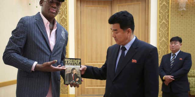 Former NBA basketball star Dennis Rodman presents a book titled "Trump The Art of the Deal" to North Korea's Sports Minister Kim Il Guk