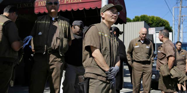 UPS workers gather outside a UPS package delivery warehouse where a shooting took place.