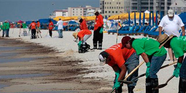 June 12: Oil cleanup workers hired by BP clean oily deposits from the shore in Orange Beach, Ala.