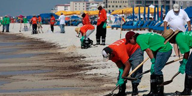 June 12: Oil cleanup workers hired by BP clean oily deposits from the shore in Orange Beach, Ala.