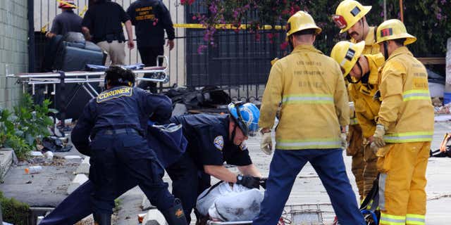 June 14, 2016: Coroner's officials and firefighters prepare to move one of four bodies found in the burned-out ruins of a abandoned office building in the Westlake district just west of downtown Los Angeles.