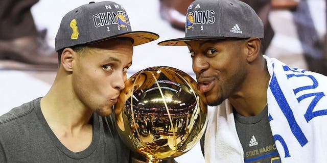 Stephen Curry #30 and Andre Iguodala #9 of the Golden State Warriors celebrate with the Larry O'Brien NBA Championship Trophy after defeating the Cleveland Cavaliers in Game Six of the 2015 NBA Finals at Quicken Loans Arena on June 16, 2015 in Cleveland, Ohio. NOTE TO USER: User expressly acknowledges and agrees that, by downloading and or using this photograph, user is consenting to the terms and conditions of Getty Images License Agreement. (Photo by Jason Miller/Getty Images)