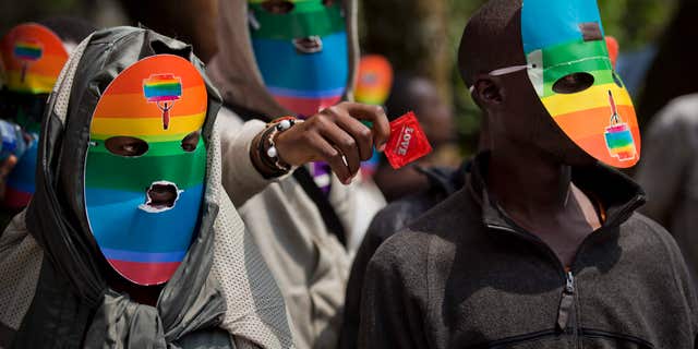 FILE - In this Monday, Feb. 10, 2014 file photo, Kenyan gays and lesbians and others supporting their cause wear masks to preserve their anonymity and one holds out a wrapped condom, as they stage a rare protest, against Uganda's increasingly tough stance against homosexuality and in solidarity with their counterparts there, outside the Uganda High Commission in Nairobi, Kenya.