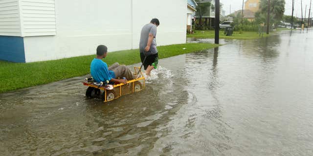June 16, 2015: Manuel Martinez pulls Jesse McGehee through high water on Saladia Street in Galveston, Texas.