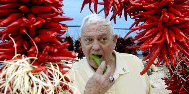FILE - In this Aug. 30, 2008 file photo, framed by ristras, John Trewitt bites into a pod of fresh Hatch green chile, at the Hatch Chile Festival in Hatch, N.M.