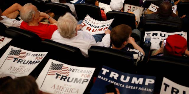 People hold signs as they wait for Republican presidential candidate Donald Trump to speak at the Treasure Island hotel and casino, Saturday, June 18, 2016, in Las Vegas.