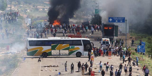 June 19, 2016: Protesting teachers who were blocking a federal highway hold their positions with a passenger bus across the road and burning trucks as they battle with riot police in the state of Oaxaca, near the town of Nochixtlan, Mexico.