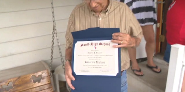 Quincel proudly holding on to his honorary high school diploma.