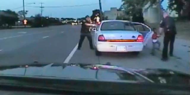 In this image made from July 6, 2016, video captured by a camera in the squad car of St. Anthony Police officer Jeronimo Yanez, the Minnesota police officer is shown after shooting into the vehicle at Philando Castile during a traffic stop in Falcon Heights, Minn., as the 4-year-old daughter of Castile's girlfriend, Diamond Reynolds, starts to get out of the car and is grabbed by an officer.