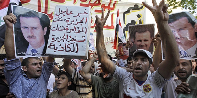 June 24: Lebanese and Syrian protesters shout slogans as they carry pictures of Syrian President Bashar Assad and Syrian flags, during a demonstration to show their support for the Syrian President in front of the Syrian embassy in Beirut, Lebanon.