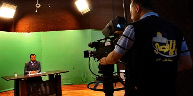 June 15: A Palestinian cameraman films a broadcaster presenting a live program at the Hamas Al Aqsa TV station in Gaza City.