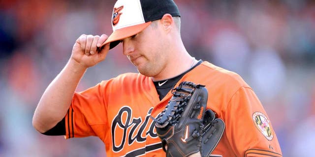 Baltimore Orioles starting pitcher Bud Norris touches the brim of his hat as he walks back to the dugout after he was pulled from the baseball game against the Toronto Blue Jays during the seventh inning Saturday, June 14, 2014, in Baltimore. The Orioles won 3-2. (AP Photo/Nick Wass)