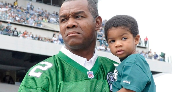 This photo made Sept. 27, 2009, shows former Philadelphia Eagles football player Randall Cunningham holding his son, Christian, during halftime of an NFL football game, in Philadelphia.