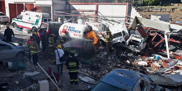FILE - In this Jan. 29, 2015 file photo, firefighters spray water on a gas truck that caused an explosion and killed five at a maternity and children's hospital in Cuajimalpa on the outskirts of Mexico City. Mexican officials said Monday, Feb. 16, 2015 that two worn-out bolts on the gas tanker truck caused a leak that resulted in the explosion. Experts said wire and Teflon tape had been improperly used on parts of the truck's valves, and Mexico City chief prosecutor Rodolfo Rios said one of the bolts was the wrong size, and the truck's gas meter had been altered to shortchange customers. (AP Photo, File)