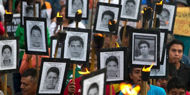 Family members of 43 missing teachers college students carry pictures of the students as they march with supporters to demand the case not be closed and that experts' recommendations about new leads be followed, in Mexico City, Tuesday, April 26, 2016. The U.N. Office of the High Commissioner for Human Rights said Tuesday that it is troubled by a group of international experts' complaints of obstacles to their investigation into Sept. 26, 2014 disappearance of the students in southern Guerrero State.(AP Photo/Rebecca Blackwell)