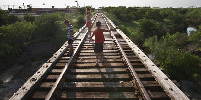 RIO GRANDE CITY, TX - AUGUST 05:  Children walk across a railroad bridge August 5, 2008 in Rio Grande City, Starr County,Texas, along the border with Mexico. By many social indicators, Starr County is the poorest county in the United States. Few of its residents have full health or dental insurance and many of them must travel across the border to Mexico in order to get medical attention and buy medicine. The two-week Operation Lone Star, run by the Texas armed forces and state health officials, provided free medical care to more than 10,000 people in areas along the Texas-Mexico border.  (Photo by John Moore/Getty Images)