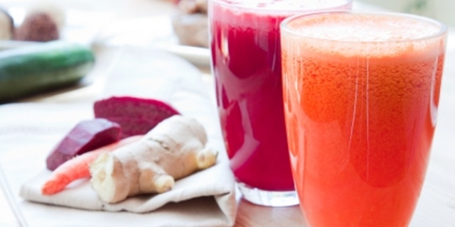 Two glasses of healthy juice - Beet, Apple, Carrot, Ginger and Orange, Apple, Pineapple. Ingredients in the background.