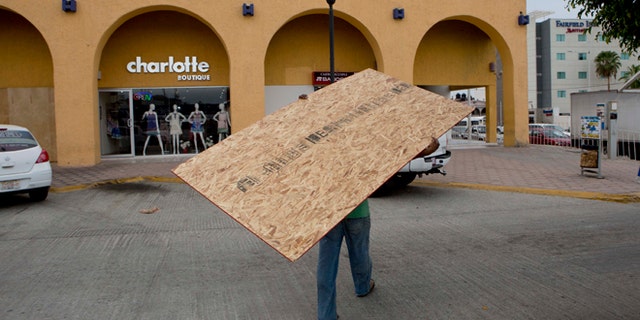 A worker hauls a board to use on a storefront window as protection against Hurricane Blanca in Cabo San Lucas, Mexico, Saturday June 6, 2015. The unpredictable Blanca, which strengthened suddenly from a Category 1 to a Category 4 storm on Saturday before weakening slightly, is expected to make landfall as a tropical storm on Monday. But authorities said its outer bands could start hitting the southern Baja California Peninsula as a hurricane on Sunday. (AP Photo/Eduardo Verdugo)