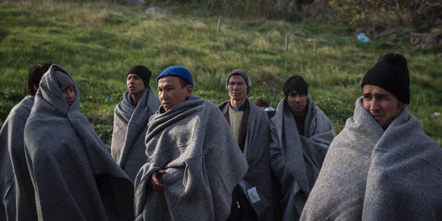 Migrants and refugees try to keep themselves warm with blankets, after the boat on which they crossed a part of the Aegean sea from Turkey hit on rocks, on the Greek island of Lesbos, on Saturday, Dec. 12, 2015. Any link between extremism and the thousands of people fleeing violence in Syria and elsewhere is false, a top European human rights official said Friday, noting that those who have perpetrated recent attacks in Europe were citizens of European countries.(AP Photo/Santi Palacios)
