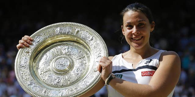 FILE - A Saturday, July 6, 2013 file photo showing Marion Bartoli of France smiling as she holds the trophy after winning the Women's singles final match against Sabine Lisicki of Germany at the All England Lawn Tennis Championships in Wimbledon, London. Three years after winning the title at Wimbledon, Marion Bartoli said she has contracted an unknown virus and her life is an "absolute nightmare." The 31-year-old Frenchwoman is now extremely thin and said it's because she is ill. (AP Photo/Anja Niedringhaus, File)