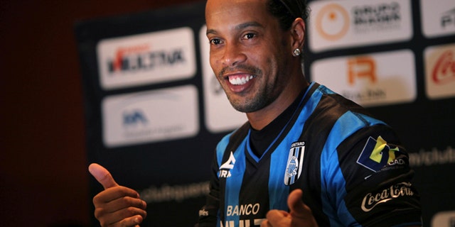 FILE - In this Sept. 12, 2014 file photo, Brazil's Ronaldinho poses for a photo after slipping on his new Queretaro soccer club jersey at a press conference in Mexico City. Mexican first-division club Queretaro signed the former 34-year-old soccer star, who had been without a club since leaving Brazil's Atletico Mineiro in July and had been negotiating with several clubs. The upbeat mood of his signing didn't last long. Even before he had played his first match, Ronaldinho became the subject of a racist attack _ the kind that have become common with black football players across Europe. (AP Photo/Marco Ugarte)