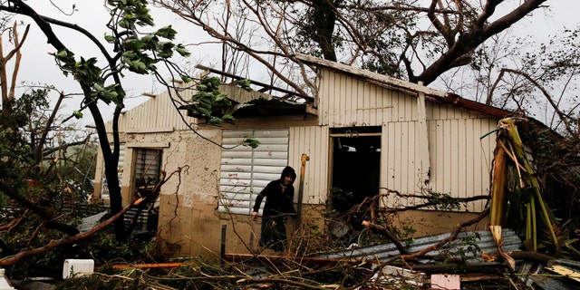 A man looks for valuables in the damaged house of a relative after the area was hit by Hurricane Maria in Guayama, Puerto Rico September 20, 2017.
