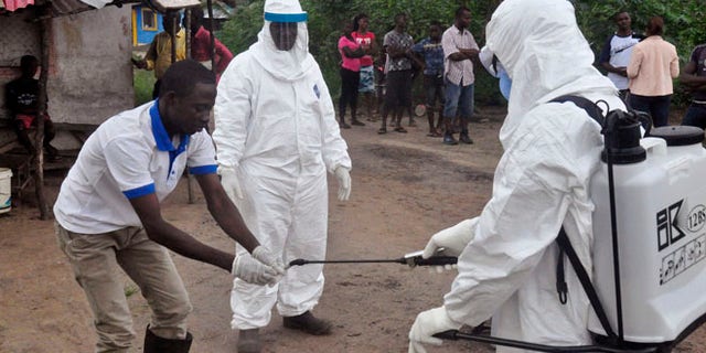June 30, 2015: Health workers wash their hands after taking a blood specimen from a child to test for the Ebola virus in an area where a 17-year old boy died from the virus on the outskirts of Monrovia, Liberia.