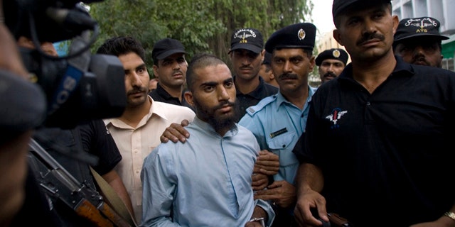 FILE - In this June 1, 2009 file photo, Pakistani police officers escort detained suspect militant Fida Ullah, center, who studied from radical Red Mosque in Islamabad, Pakistan. Pakistani authorities now believe a dangerous new militant group, out to avenge a deadly army assault on the mosque three years ago, has carried out several major bombings in the capital previously blamed on the Taliban. (AP Photo/Anjum Naveed, File)