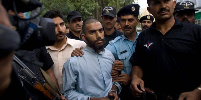 FILE - In this June 1, 2009 file photo, Pakistani police officers escort detained suspect militant Fida Ullah, center, who studied from radical Red Mosque in Islamabad, Pakistan. Pakistani authorities now believe a dangerous new militant group, out to avenge a deadly army assault on the mosque three years ago, has carried out several major bombings in the capital previously blamed on the Taliban. (AP Photo/Anjum Naveed, File)