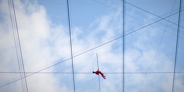 Adili Wuxor lies on a tightrope during the last day of his two-month tightrope walking performance on top of China's National Stadium, also known as the Bird's Nest, in Beijing, China, Friday, July 2, 2010. Adili, an Uighur ethnic Dawaz tightrope walking performer, has been walking the tightrope five hours a day on the top of the Bird's Nest over the past 60 days, setting a new Guinness World Record. (AP Photo/Alexander F. Yuan)