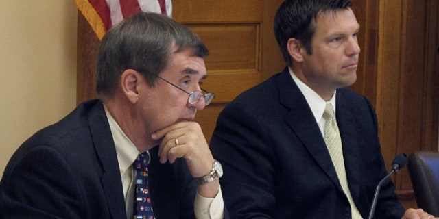 June 30: Kansas Secretary of Administration Dennis Taylor, left, and Secretary of State Kris Kobach, right, listen to a presentation on new regulations for abortion clinics at the Statehouse in Topeka, Kan.