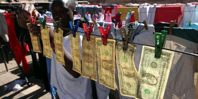 July 6: Alex Mupondi hangs dollar bills on a drying line after washing them in Harare -- Zimbabwe's style of laundering dirty money.