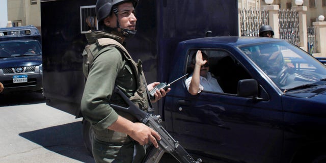 July 5: An Egyptian soldier secures the road as police prisoner vehicles transport three Mubarak-era ministers out of the Supreme State Security Court after attending their trial session in Cairo, Egypt.