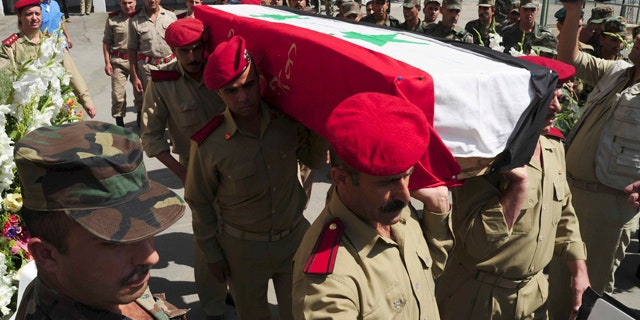 July 6: In this photo released by the Syrian official news agency SANA, Syrian soldiers carry the coffin of a comrade who was killed in recent violence in the country during his funeral procession at a hospital in Damascus, Syria.