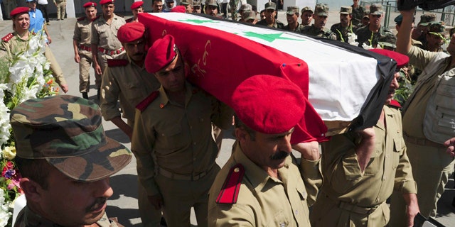 July 6: In this photo released by the Syrian official news agency SANA, Syrian soldiers carry the coffin of a comrade who was killed in recent violence in the country during his funeral procession at a hospital in Damascus, Syria.