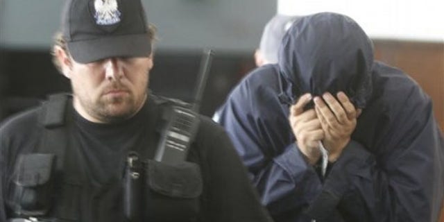 July 5: Hiding his face, Israeli citizen Uri Brodsky is escorted by police officials to a court session in Warsaw.