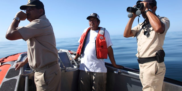 July 6: Fisherman Jesus Rodrigo Fernandez, center, a member of the crew of the fishing boat that capsized last Sunday, helps Navy personnel in the search and rescue efforts in Punta Bufeo.