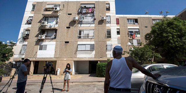 July 9, 2015: Israeli journalists report outside the apartment building of Ethiopian-Israeli Avraham Mengisto, 28, in the costal city of Ashkelon, Israel.
